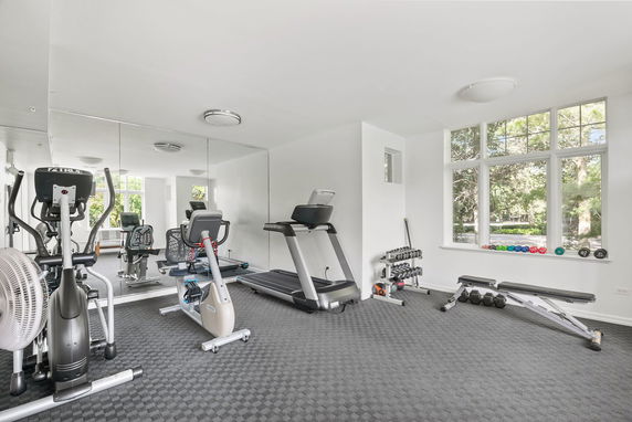 Indoor gym with exercise equipment and mirrored walls.