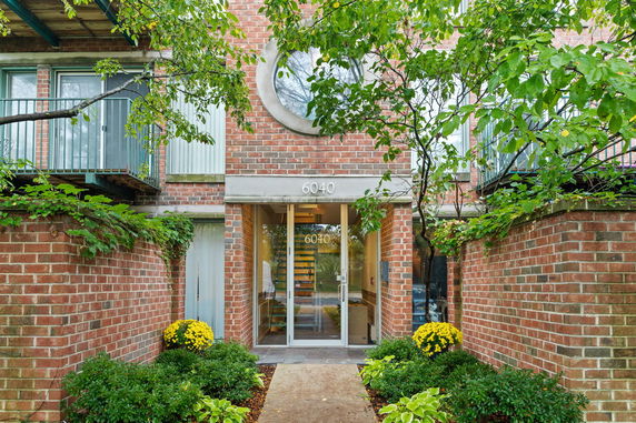 Front view of a brick building with glass entrance and balconies.