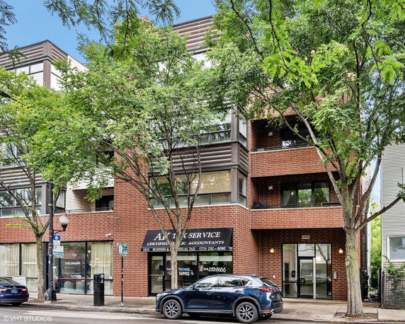 Front view of a multi-story brick building with large windows.