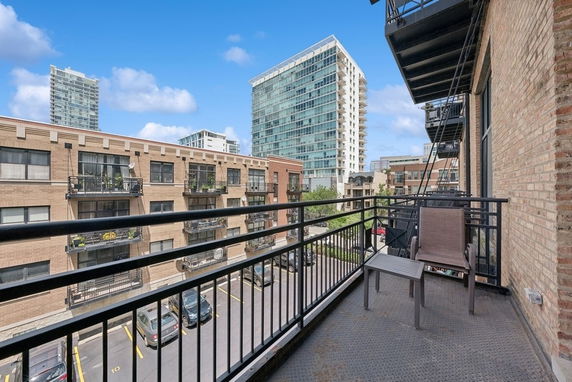 View from a balcony showing nearby buildings and a parking area.