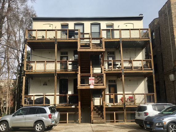 Rear view of a multi-story building with wooden balconies.