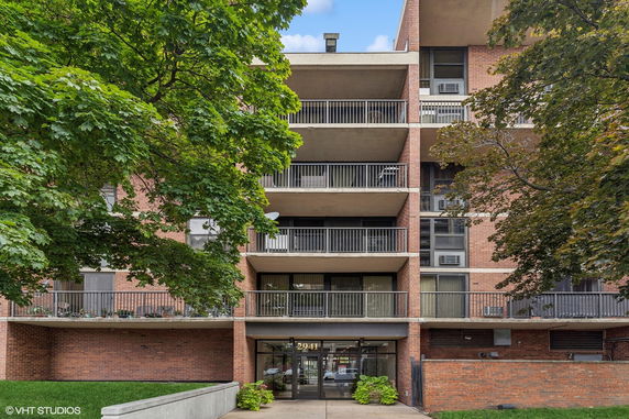 Front view of a multi-story brick apartment building with balconies.