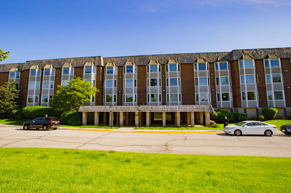 Front view of a multi-story building with large windows and a covered entrance area.