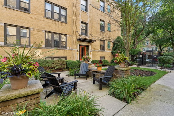 Front view of a multi-story brick apartment building with a small patio area.