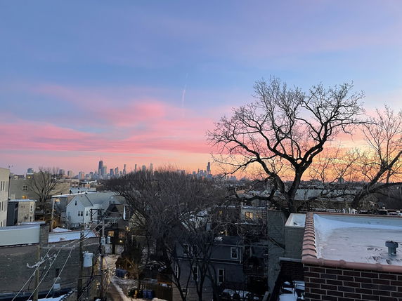 Wide-angle view from a rooftop showing a city skyline at sunset.