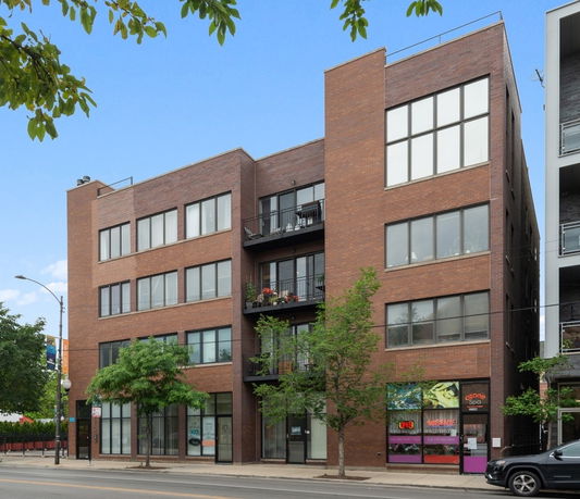 Front view of a multi-story brick building with large windows and balconies.