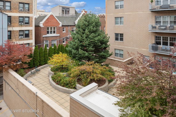 Rooftop view with landscaped garden and adjacent buildings.