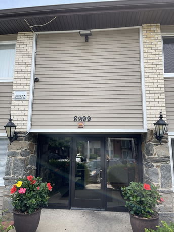 Front view of a building entrance with glass doors and stone facade.