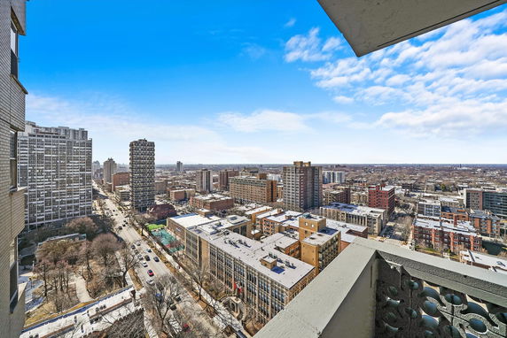 Panoramic view of a cityscape from a high vantage point, featuring multiple buildings and streets.