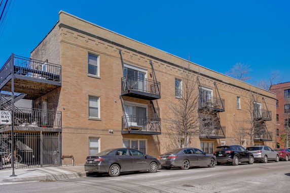 Front view of a multi-story apartment building with brick exterior and balconies.