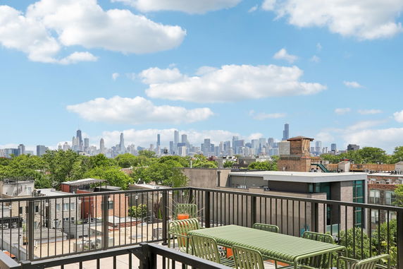 Panoramic view of a city skyline from a rooftop with outdoor furniture.