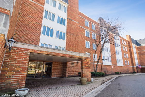 Front view of a multi-story brick apartment building with a covered entryway.
