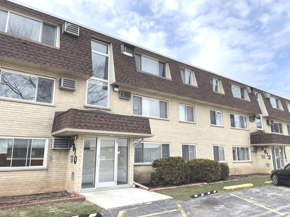 Front view of a multi-story apartment building with brick exterior and multiple windows.