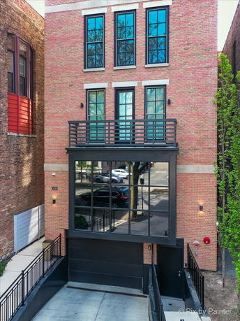 Front view of a multi-story brick building with large windows and a garage entrance.