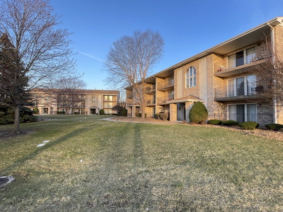 Front view of a multi-story apartment building with balconies and arched windows.