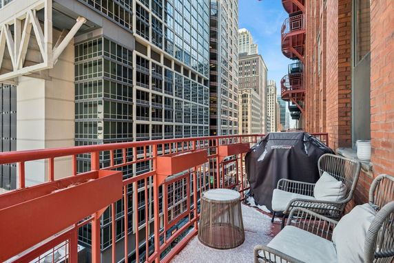 View of surrounding buildings from a balcony with outdoor furniture and a grill.