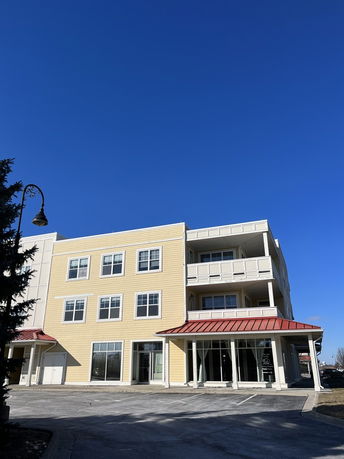 Front view of a three-story building with large windows and red awnings.