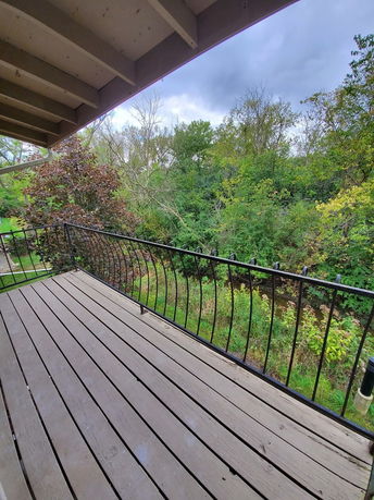 View from a wooden balcony overlooking trees and greenery.