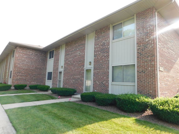 Front view of a two-story brick building with trimmed bushes and lawns.