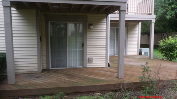 View of a house exterior with wooden deck and sliding doors.