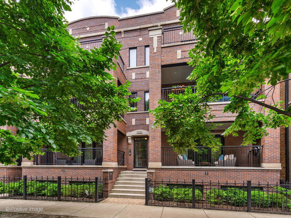 Front view of a multi-story brick building with balconies and greenery.