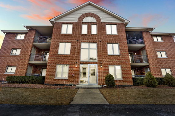 Front view of a multi-story brick apartment building with balconies.