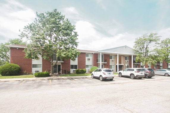 Front view of a two-story brick apartment building with a parking area.
