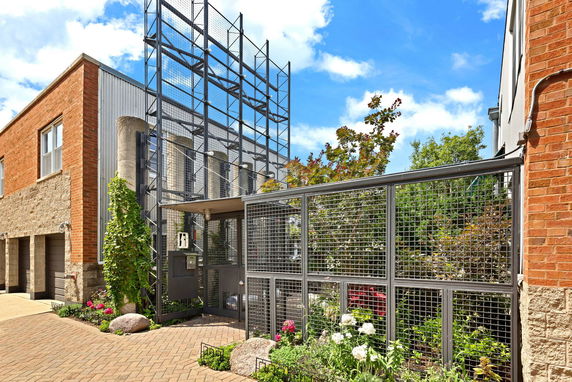 Front view of a building with brick and metal exterior and mesh fencing.