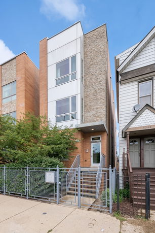 Front view of a modern multi-story house with a staircase leading to the entrance.