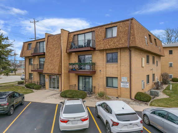 Front view of a three-story brick apartment building with balconies.