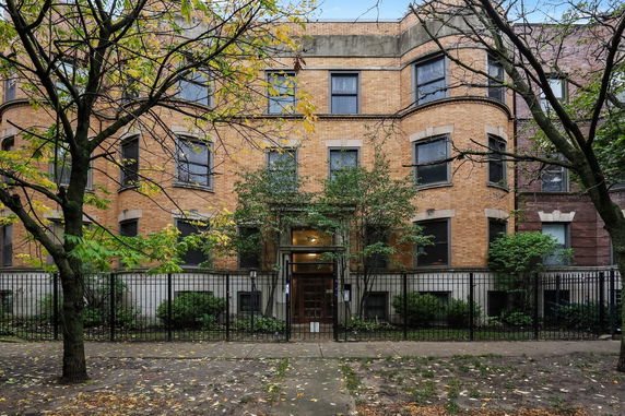 Front view of a three-story brick apartment building with multiple windows.
