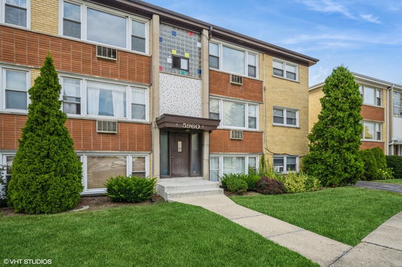 Front view of a three-story apartment building with a brick facade and central entrance.