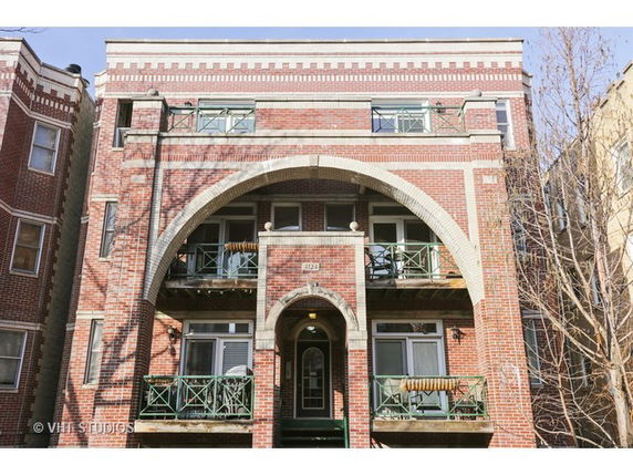 Front view of a multi-story brick apartment building with balconies.