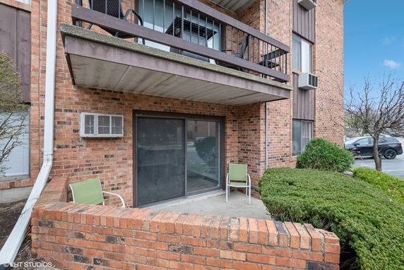 Front view of a brick building with a small patio and balcony.