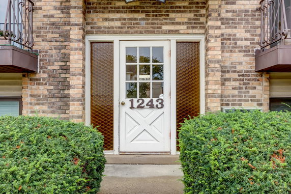 Front view of a brick house entrance with a white door and house number 1243.