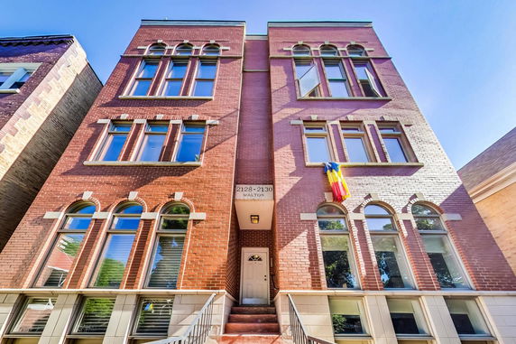 Front view of a multi-story brick building with arched windows.