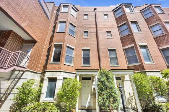 Front view of a multi-story brick building with multiple windows and entryway.