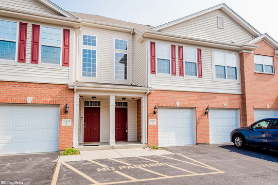 Front view of a multi-story building with red shutters and double garages.