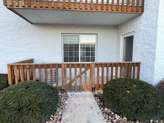 Front view of a building with a small patio and wooden railing.