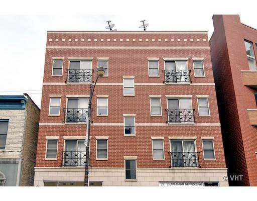 Front view of a multi-story red brick apartment building with small balconies.