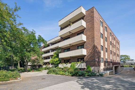 Front view of a multi-story residential building with balconies and brick facade.