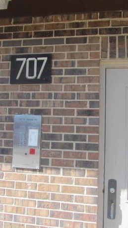 Brick exterior with a door and a sign displaying the number 707.