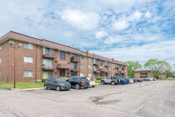 Parking area in front of a multi-story apartment building.