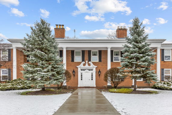 Front view of a two-story brick house with white columns and chimneys.