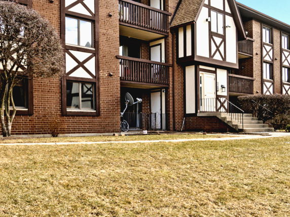 Front view of a multi-story apartment building with brick and wood accents.