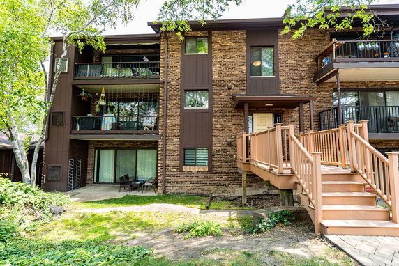 Front view of a multi-story building with balconies and a wooden ramp.