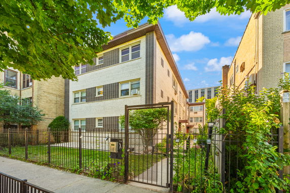 Front view of a multi-story residential building with a fenced yard.