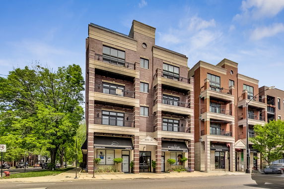 Front view of a multi-story building with balconies and brick facade.