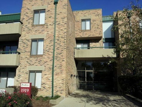 Front view of a multi-story brick building with balconies and a glass entrance.