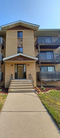 Front view of a multi-story building with balconies and entrance stairs.